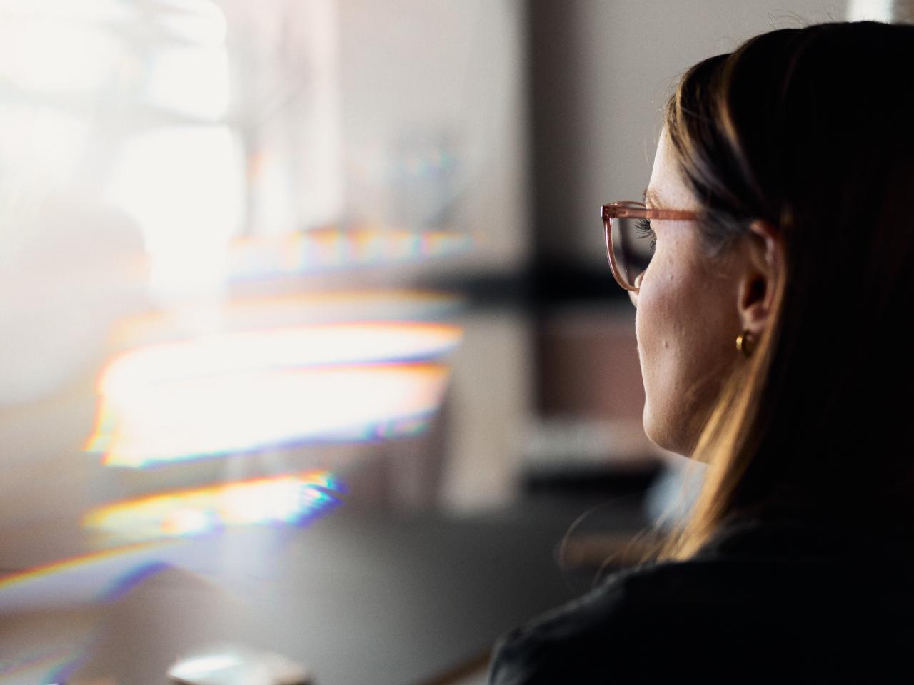 Person vor Bildschirm im Büro, Fokus auf Gesicht im Profil.