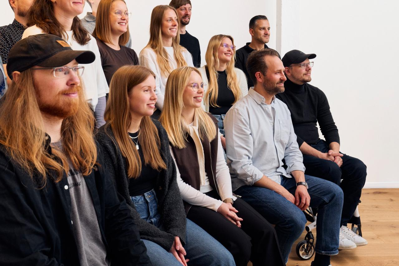 Gruppe von Mitarbeitenden sitzt nebeneinander in einem Raum und schaut aufmerksam nach vorn.